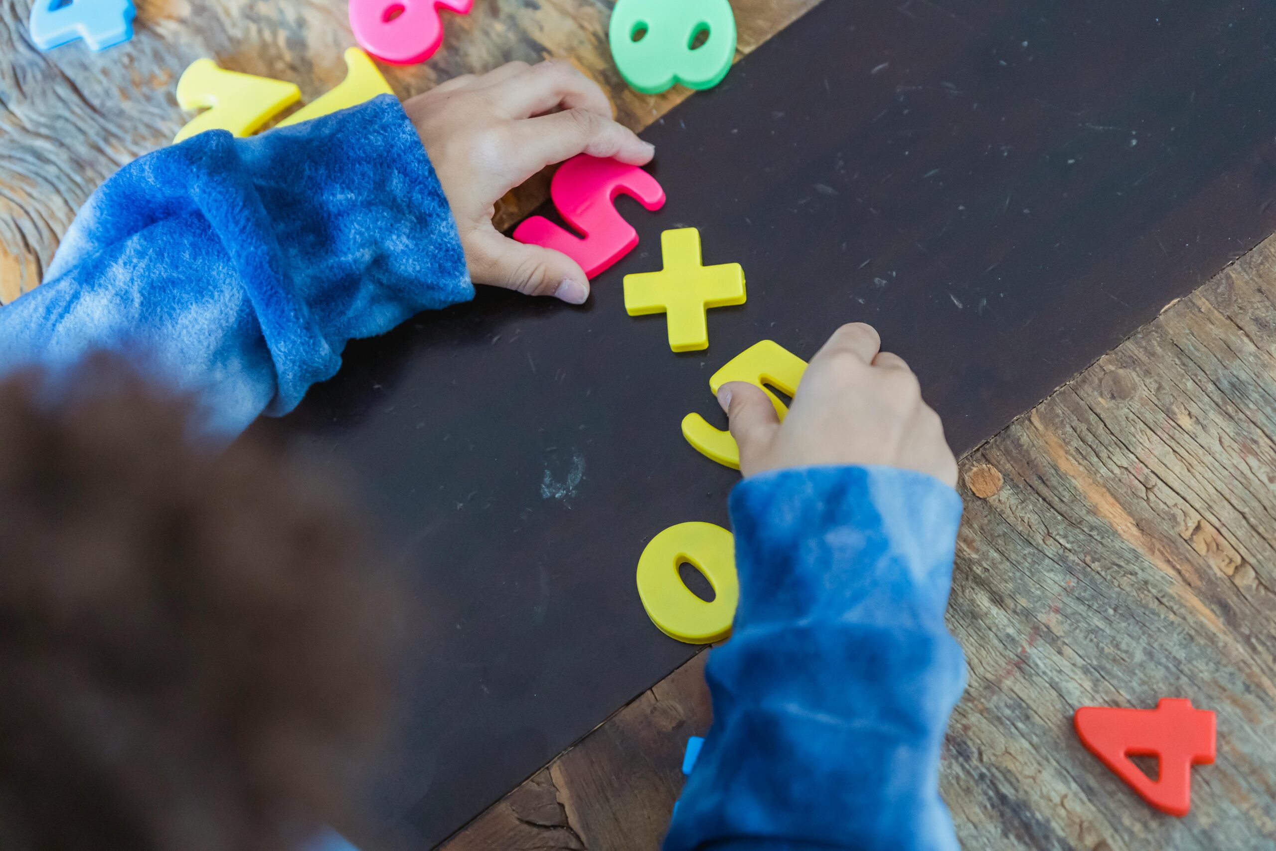 A child playing with colorful number magnets on a wooden table, promoting early education.
