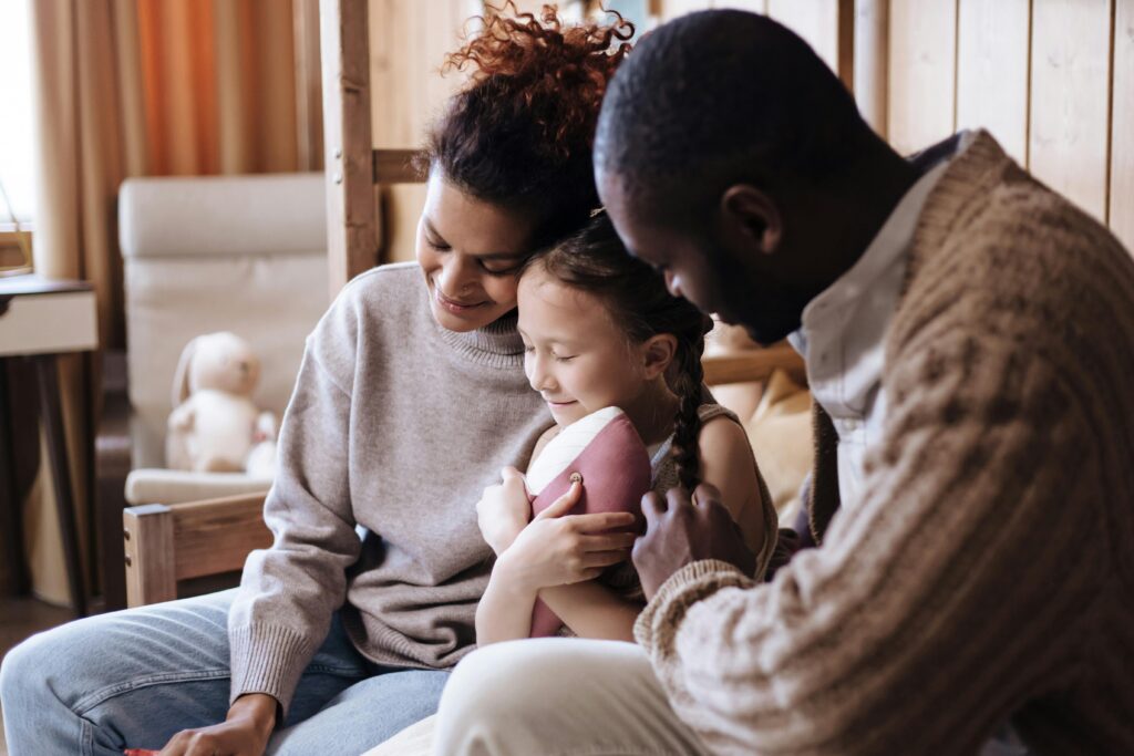 Warm family moment indoors with parents embracing their child, promoting joy and togetherness.